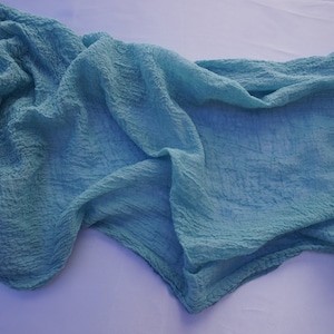 May include: A light blue crinkled fabric scarf. The fabric is soft and has a textured look.