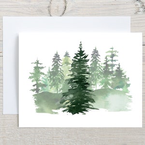 May include: A white greeting card with a watercolor painting of a forest scene. The artwork features several green pine trees of varying shades, creating a layered effect. The card is accompanied by a white envelope.