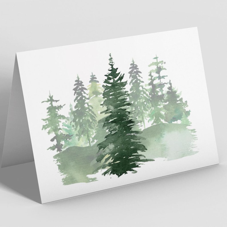 Puede incluir: Una tarjeta de felicitaci&oacute;n plegada con una pintura de acuarela de una escena de bosque. La obra de arte representa varios &aacute;rboles de hoja perenne en tonos verdes, con un fondo suave y borroso. La tarjeta es blanca.