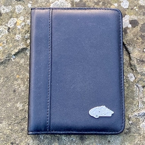 May include: A black leather wallet with a silver metal emblem of a spaceship on the front.