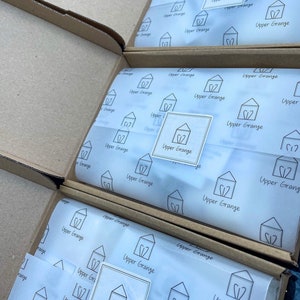May include: Three cardboard boxes with white tissue paper inside. The tissue paper has a repeating pattern of a house with a heart and the text "Upper Grange".