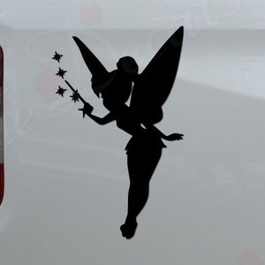 May include: Black silhouette decal of a fairy with outstretched arms holding a wand with stars. The decal is affixed to the side of a white truck. The text "Rosie Decals" is visible on the bumper.