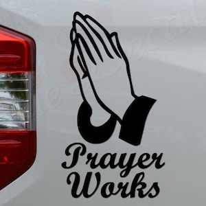 May include: Black and white decal of praying hands with the text "Prayer Works" on a white truck tailgate.