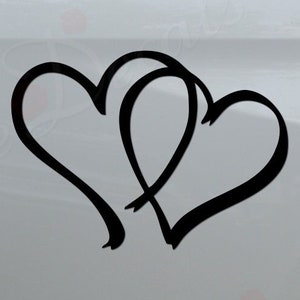 May include: A white truck with a black decal of two intertwined hearts on the back. The decal is on the right side of the truck bed. The truck has a black bumper with the words "Rosie Decals" in red letters with small red roses around the text.