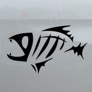 May include: Black fish skeleton decal on a white truck. The decal is on the back of the truck, near the taillight. The decal is a stylized fish skeleton with a sharp, pointed fin. The decal is a popular choice for truck owners who enjoy fishing.