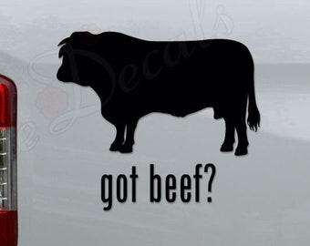 May include: Black silhouette of a cow with the text "got beef?" on a white truck tailgate.