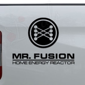 May include: A white pickup truck with a black decal on the back. The decal features a stylized symbol with a circle and lines, and the text "MR. FUSION HOME ENERGY REACTOR".