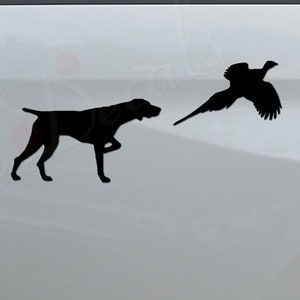 May include: Black silhouette of a dog pointing at a pheasant, with the text "Rosie Decals" on the bottom of a white truck.