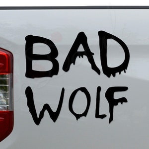 May include: A white pickup truck with a black decal that says "BAD WOLF" on the back.