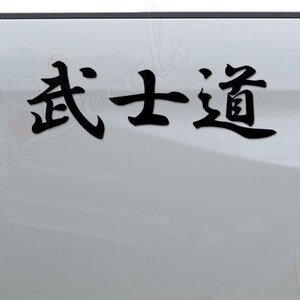 May include: A white pickup truck with a black decal on the back that says "武士道" in Japanese characters.