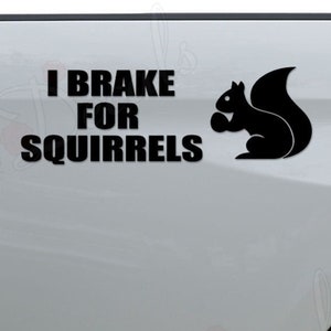 May include: A white pickup truck with a black decal that says "I Brake For Squirrels" and a silhouette of a squirrel holding a nut.