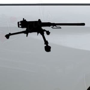 May include: A black silhouette of a machine gun decal on the back of a white pickup truck.