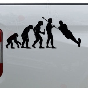 May include: Black vinyl decal depicting the evolution of man, culminating in a lacrosse player. The decal is applied to the side of a white truck, showcasing the silhouette design. The taillight is visible.