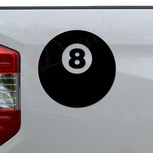 May include: A black and white 8-ball decal on a white truck tailgate.
