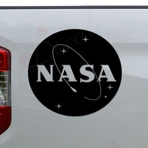 May include: A white pickup truck with a black and white NASA logo decal on the back.
