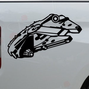May include: Black vinyl decal of the Millennium Falcon spaceship, applied to the side of a white truck. The decal is a detailed silhouette of the iconic spacecraft from the Star Wars franchise.