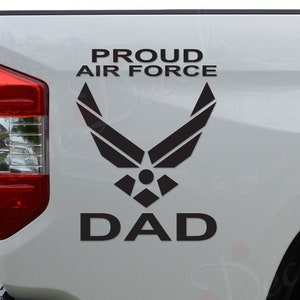 May include: A white truck with a black decal that says "Proud Air Force Dad" with the Air Force logo.