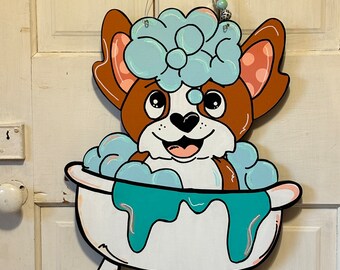 May include: A cartoon dog with brown ears and a white body is taking a bath in a white bathtub with blue water and white bubbles. The dog has blue eyes and a pink nose. The dog is wearing a blue and white shower cap.