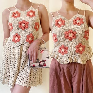 Puede incluir: Un top de crochet halter con un diseño floral en tonos crema y coral. El top tiene un dobladillo festoneado y está hecho con un punto de crochet delicado.