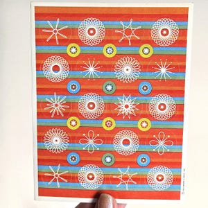 May include: A vintage Hallmark greeting card with a repeating pattern of white geometric shapes and circles on a red and striped background. The card has a retro design with a variety of shapes and colors.