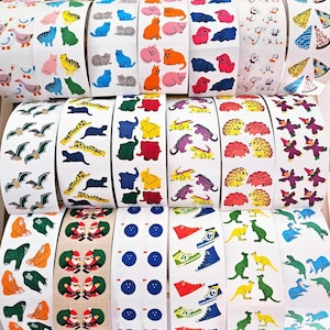 May include: A collection of adhesive sticker rolls featuring various colorful illustrations including animals like cats, dogs, elephants, hedgehogs, and kangaroos, as well as objects such as sneakers, bowling balls, and holiday figures on white backing.