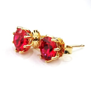 Puede incluir: Un par de pendientes de oro con piedras preciosas rojas. Los pendientes tienen un diseño sencillo y son perfectos para el uso diario.