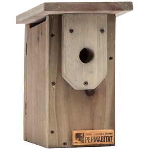 May include: A wooden birdhouse with a round entrance hole. The birdhouse is made of natural wood and has a brown stain. The birdhouse has a small roof and a small platform on the front. The birdhouse has a label on the bottom that says "Paysage Connectable et Durable PERMABITAT".