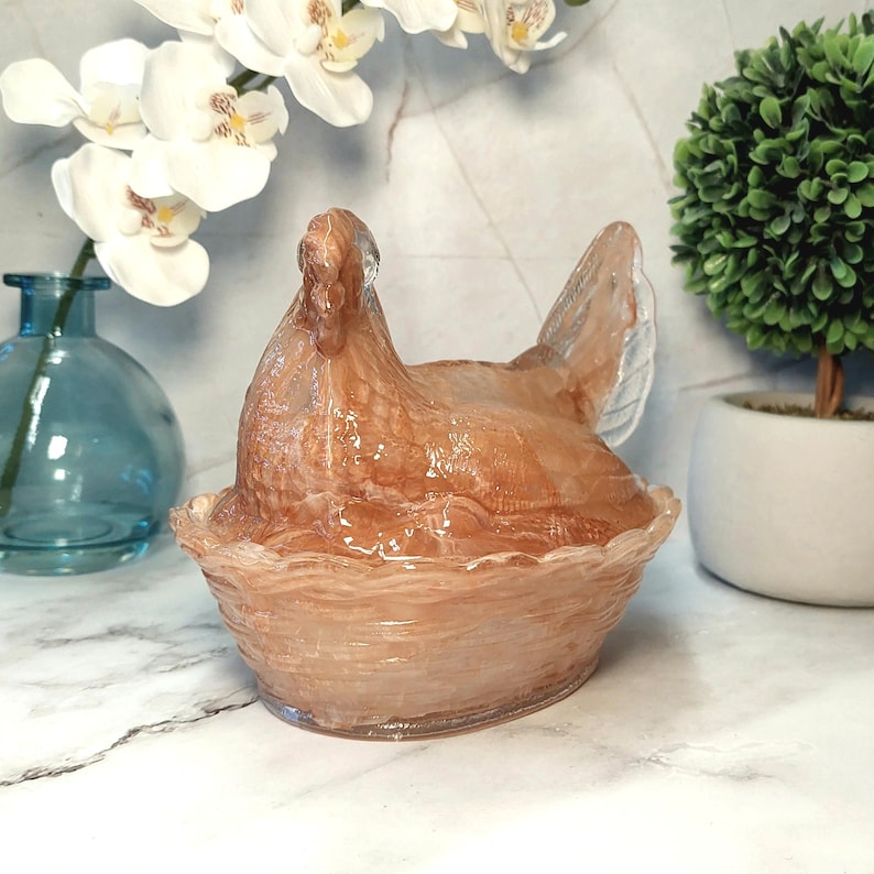 May include: A decorative, translucent hen figurine in a nest-like bowl. The hen is a light brown color with a textured surface. The bowl has a wavy rim. The figurine is a unique home decor item.