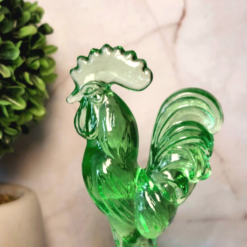 May include: A green glass rooster figurine with a detailed comb and tail feathers.