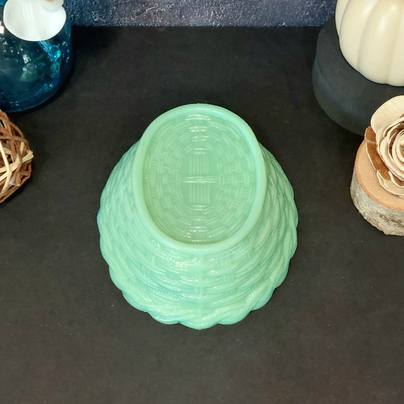 May include: A light green, basket-weave patterned bowl. The bowl is upside down, revealing the woven texture on the bottom. The bowl's edges have a scalloped design. The bowl is made of glass or a similar material.