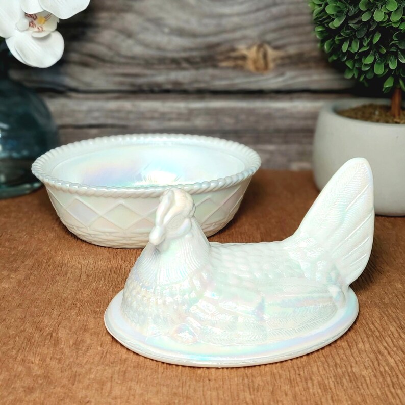 May include: An iridescent white milk glass hen on a nest dish with a matching separate bowl. The hen lid features detailed feather textures and a raised comb, while the round bowl has a textured diamond pattern and a rope-style rim edge.