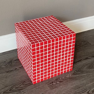 May include: Red cube-shaped stool covered in small red and white square tiles.