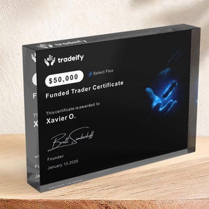Puede incluir: Un bloque rectangular de acr&iacute;lico negro que muestra un certificado de trader financiado de Tradeify por $50,000. El certificado presenta el nombre Xavier O., una firma del fundador Brett Simberkoff, la fecha 13 de enero de 2026 y un gr&aacute;fico azul brillante.