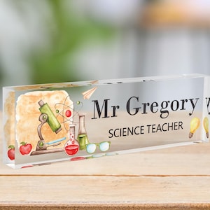 May include: Clear acrylic desk nameplate with a watercolour illustration of a microscope, beakers, and apples. The text "Mr. Gregory Science Teacher" is printed in black.