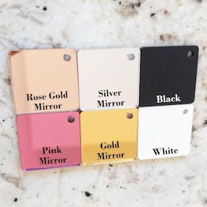 Puede incluir: Una colecci&oacute;n de seis muestras de color acr&iacute;licas cuadradas. Los colores incluyen Rose Gold Mirror, Silver Mirror, Black, Pink Mirror, Gold Mirror y White. Cada muestra tiene un peque&ntilde;o agujero y etiquetas de texto.