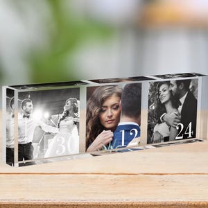 Op de afbeelding: Een heldere glazen blok met drie foto's van een stel op hun trouwdag. De foto's zijn in een rij gerangschikt en elke foto heeft een nummer erop: 30, 12 en 24.