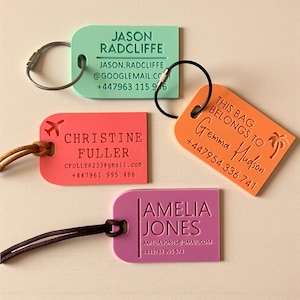 Peut inclure: Quatre étiquettes de bagages colorées, vertes, corail, orange et rose, avec des coins arrondis. Chaque étiquette porte un nom, des coordonnées et un élément de design unique, comme un avion ou un palmier.