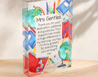 May include: A clear acrylic block with a watercolor design featuring school supplies and the text "Mrs Gentles". The block includes images of globes, books, pencils, and the message: "Thank you for your dedication, patience, and guidance."
