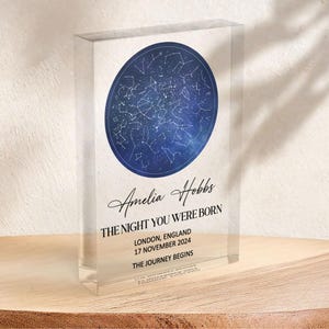 May include: A clear acrylic block with a blue celestial map design. The text reads "Amelia Hobbs, The Night You Were Born, London, England, 17 November 2024, The Journey Begins."