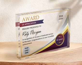Puede incluir: Una placa de premio de acrílico transparente con un diseño dorado y morado. El texto "AWARD OF APPRECIATION" está impreso en dorado. El texto "PROUDLY PRESENTED TO Katy Morgan" está impreso en negro. El texto "In recognition of 10 years of dedicated service to the team. Congratulations on your incredible achievement." está impreso en negro. El texto "YOUR LOGO HERE" está impreso en gris. El texto "2024 AWARD" está impreso en blanco. El texto "10 years" está impreso en blanco sobre una estrella dorada.