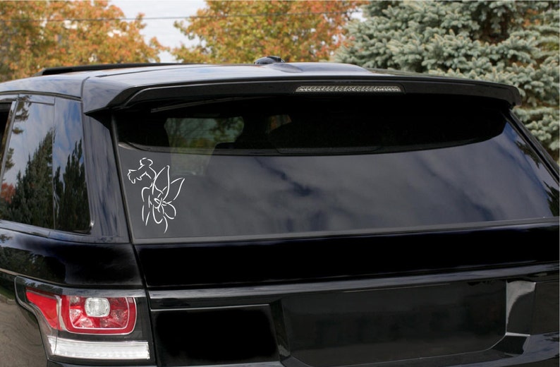 May include: A white outline of a flower with leaves is on the back window of a black SUV.