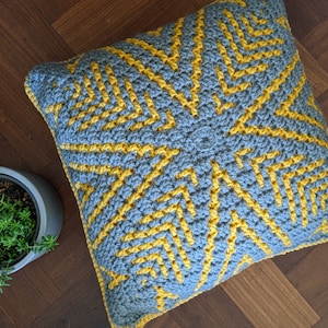 May include: A grey and yellow crocheted cushion with a geometric pattern.