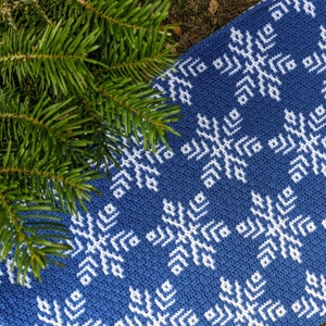 May include: A blue and white crocheted rug with a geometric snowflake pattern. The rug is made with a soft, textured yarn.