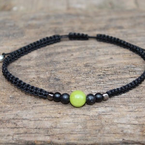 May include: A black cord bracelet with a green stone bead and two black beads.