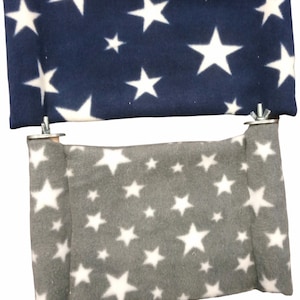 May include: Two hanging pet beds with white stars on a blue and grey background. The beds are made of soft fabric and have a rope-like hanging system.