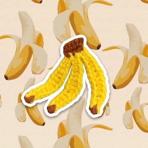 Puede incluir: Un pl&aacute;tano de crochet con una punta marr&oacute;n. El pl&aacute;tano est&aacute; hecho de hilo amarillo y tiene una forma tridimensional.