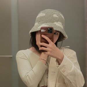 Może przedstawiać: Osoba w zielono-białym, dzianym kapeluszu typu bucket z brązowym etui na telefon. Etui na telefon ma fakturowany wz&oacute;r i widoczny napis "THE CASE FACTORY".