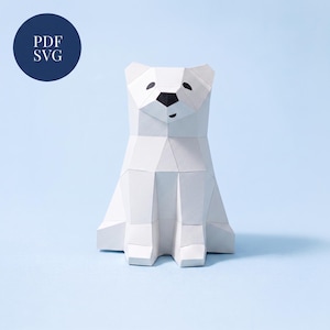 Könnte beinhalten: Eine Eisbären-Skulptur aus Papier mit einem geometrischen, facettierten Design. Der Bär hat eine schwarze Nase und schwarze Augen. Ein dunkelblaues kreisförmiges Abzeichen in der oberen linken Ecke enthält den weißen Text PDF SVG für Dateiformate.