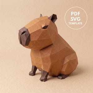 Puede incluir: Una escultura de papel low-poly de un capibara en tonos marrón claro y oscuro. La figura presenta un diseño geométrico facetado con nariz y patas de color marrón oscuro. Un círculo blanco en la esquina superior derecha contiene el texto PDF SVG TEMPLATE.