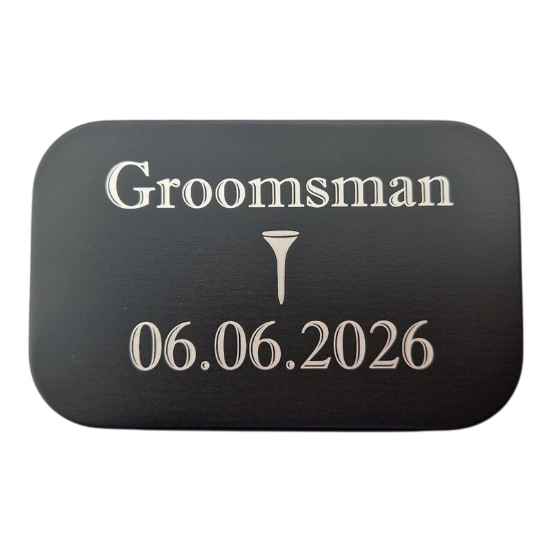 May include: A black rectangular plaque with rounded corners. The word "Groomsman" is at the top, with a golf tee symbol below it. The date "06.06.2026" is at the bottom in a white, elegant font.